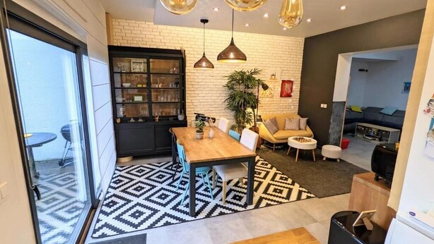 Een moderne woonkamer met een houten eettafel, een bank en een zwarte boekenkast.