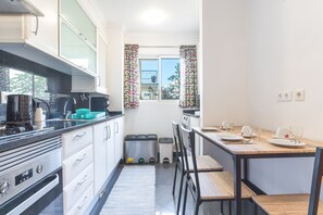 Une cuisine compacte équipée d’une cuisinière, d’une machine à café et d’une petite table à manger avec des chaises.