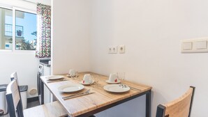 A dining table with plates, cutlery, and glasses, a chair, and a window with a curtain.