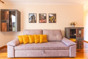 A living room with a sofa, a wooden cabinet, and three framed pictures on the wall. - Judite Home Apartment by Atlantic Holiday (Santa Cruz)