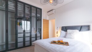 Una camera d'albergo con un letto grande, un armadio con ante in vetro e un vassoio con prodotti per la colazione.