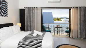 A hotel room with a bed, a balcony with a table and chairs, and an air conditioning unit on the wall. - Cozy 2-bedroom apartment in adorable Wailoaloa Beach (Nadi)