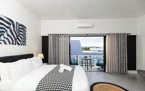 Ein Hotelzimmer mit Bett, Außenblick, Balkon und Tisch mit Stühlen.