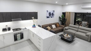 A modern kitchen with white cabinetry, a marble island, and a built-in oven. - Cozy 2-bedroom apartment in adorable Wailoaloa Beach (Nadi)