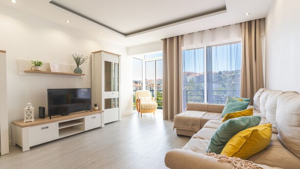 A modern living room with a TV, sofa, and a view of the city. - Sol Garajau Apartment by Atlantic Holiday (Santa Cruz)