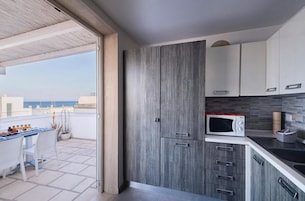 Una cocina moderna con armarios grises, un microondas y un comedor con mesa y sillas.