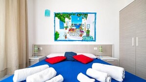 A hotel room with a bed, two nightstands, a large painting, and a wardrobe. - La Terrazza sul Porto B&B (San Foca)