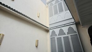 A courtyard with white walls, a metal gate, and a clear blue sky. - Riad Blue Berry (Marrakech)