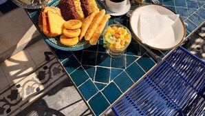 A breakfast setup on a tiled outdoor table with a variety of food items, including fruits, pastries, and beverages. - Riad Blue Berry (Marrakech)