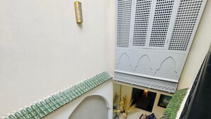 A courtyard with a swimming pool, green bottle-shaped planters, and a white wall with decorative patterns. - Riad Blue Berry (Marrakech)