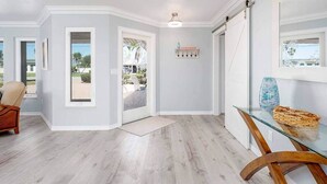 Un interior moderno con piso de madera clara, una mesa de vidrio y una silla.