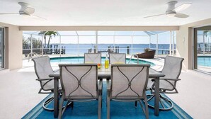 Un área de comedor con vista a la piscina, que incluye una mesa con sillas, un tapete azul y una botella de agua.