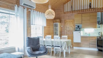 Una cocina moderna con armarios de madera, un comedor con mesa y sillas, y un sofá gris.