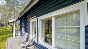 A wooden deck with two lounge chairs and a covered porch area.