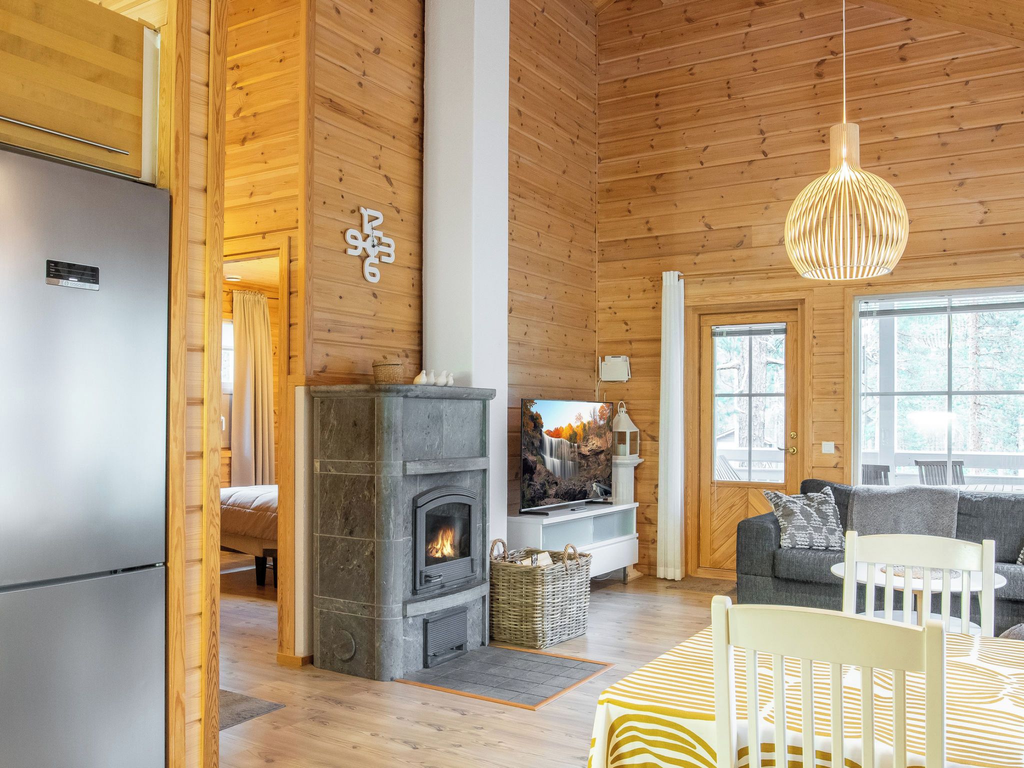 A wooden interior with a fireplace, a television, and a dining area.