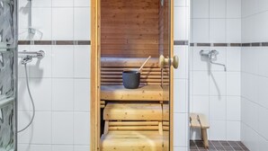 A sauna with a wooden bench, a bucket, and a small stool.