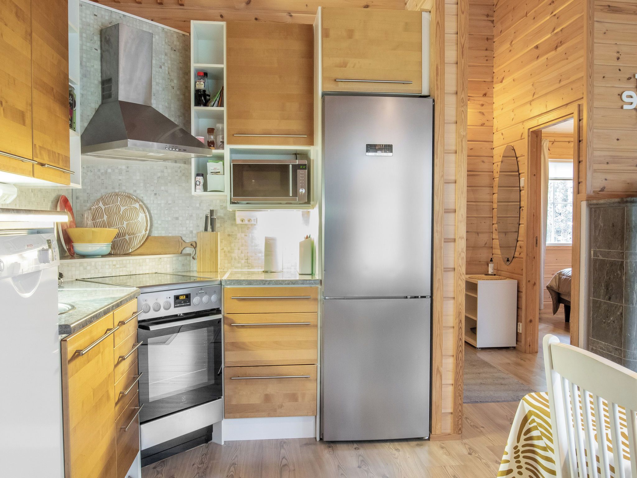 Een moderne keuken met een roestvrijstalen koelkast, een ingebouwde oven, een magnetron en houten keukenkastjes.