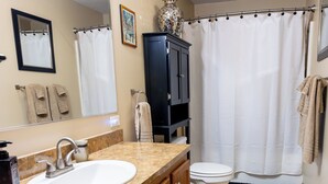 Ein Badezimmer mit Waschbecken, Spiegel, Toilette und Duschvorhang.