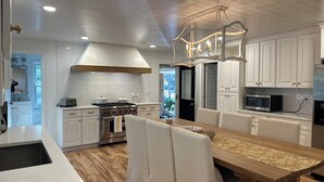 A modern kitchen with white cabinetry, a wooden dining table, and a built-in oven. - Golf course home in Raintree Country Club. Outdoor oasis with pool and hot tub. (Charlotte)