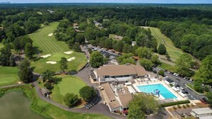 An aerial view of a golf course with a swimming pool and a clubhouse. - Golf course home in Raintree Country Club. Outdoor oasis with pool and hot tub. (Charlotte)