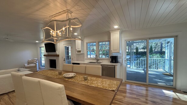 A modern kitchen with a wooden dining table, white cabinetry, and a large window overlooking a deck. - Golf course home in Raintree Country Club. Outdoor oasis with pool and hot tub. (Charlotte)