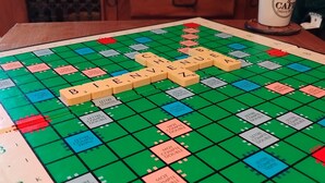 Un gioco da tavolo Scrabble su un tavolo di legno, con una tazza di caffè nelle vicinanze.