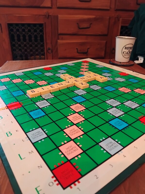 Ein Scrabble-Spiel auf einem Holztisch, in der Nähe steht eine Kaffeetasse.