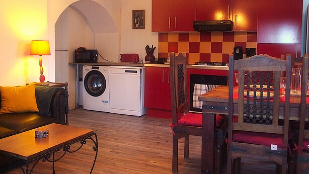 Un ambiente compatto con lavatrice, un tavolo da pranzo con sedie, un divano e una lampada.