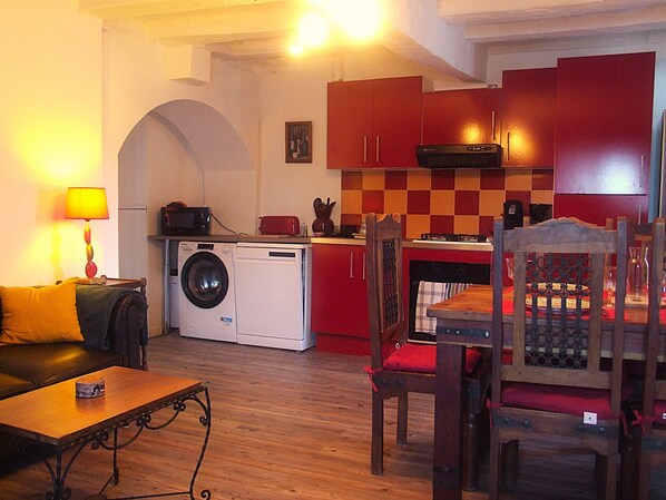 A compact living space with a washing machine, a dining table with chairs, a sofa, and a lamp. - Gite Chez Béa *** stars 5 minutes from La Roche-Posay  (Pleumartin)