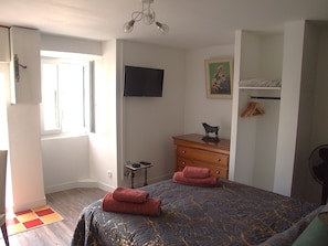 A bedroom with a bed, a dresser, a television, a painting, and a window. - Chez Béa*** Vacation Rental: fenced-in yard, dogs welcome, quiet, all-inclusive rate (Pleumartin)