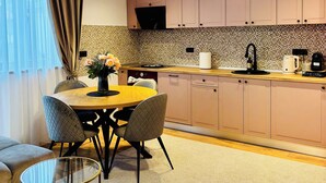 Una cocina moderna con comedor, que incluye una mesa redonda, sillas y una lámpara geométrica original.