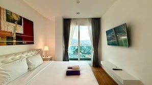 Ein Hotelzimmer mit Bett, Fernseher, Fenster mit Vorhängen und Blick auf die Stadt.