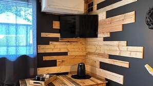 Une cuisine moderne avec une table en bois, une bouilloire noire et un téléviseur fixé au mur.