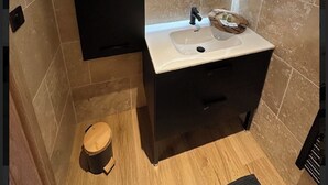 Une salle de bain moderne avec un miroir rond, un lavabo et des toilettes.