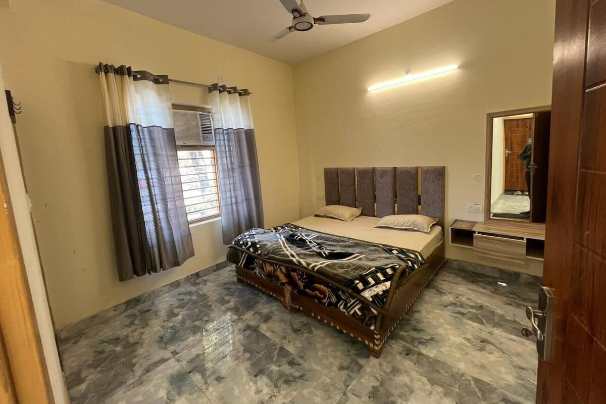 A bedroom with a bed, curtains, a ceiling fan, and a mirror.