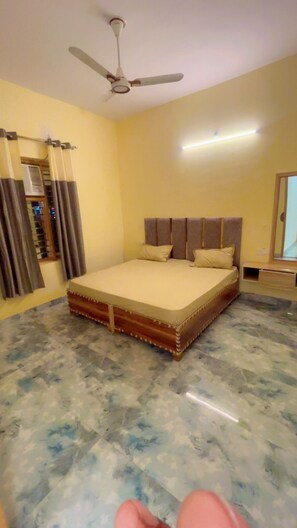 A bedroom with a bed, a ceiling fan, and a window with curtains. - Maharaja Hotel and Dhaba (Roorkee)