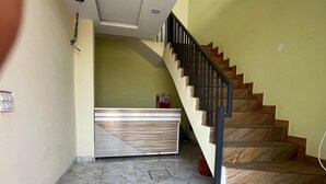 Escada com degraus de madeira e corrimão de metal que leva a uma área de recepção com balcão estampado.