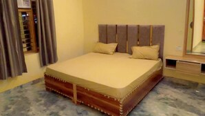 Quarto com cama, ventoinha no teto, espelho e janela com cortinas.