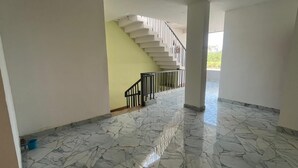 Um interior espaçoso com piso de mármore, uma escadaria e uma parede amarela.