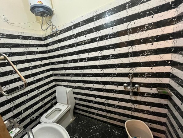 A small bathroom with a toilet, a bidet, and a handrail. - Maharaja Hotel and Dhaba (Roorkee)