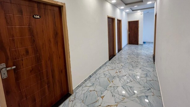 Um corredor com portas de madeira, numeradas 106, e chão de mármore.