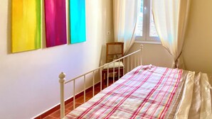 A bedroom with a bed, a window with curtains, and three colorful paintings on the wall. - Bed&Breakfast by the sea 1 double room/2 persons (Kryevidh)