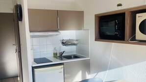 Une cuisine compacte équipée d’un réfrigérateur, d’un four à micro-ondes, d’un évier et d’une petite fenêtre.