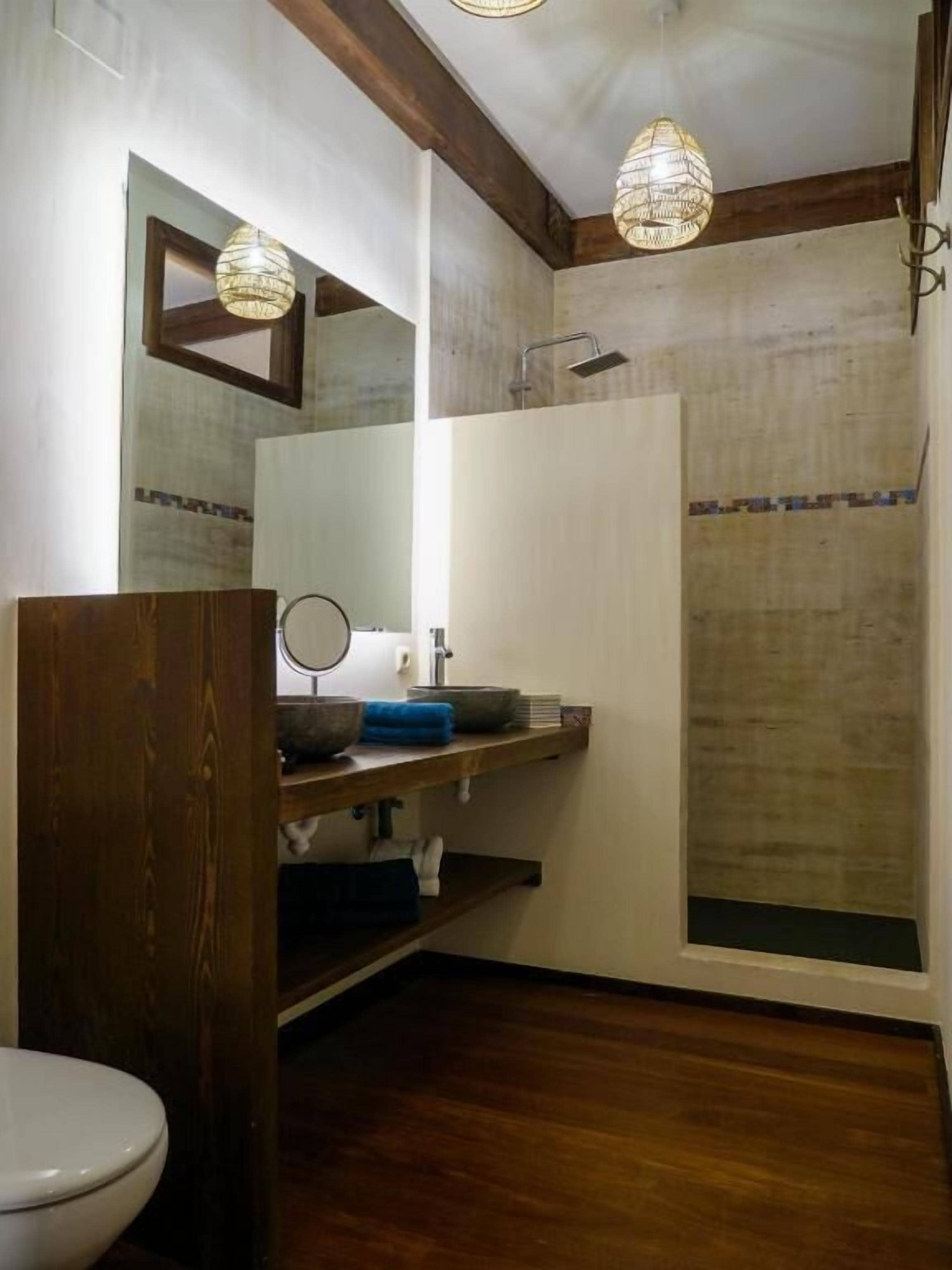 A bathroom with a wooden vanity, a mirror, a sink, and a shower.