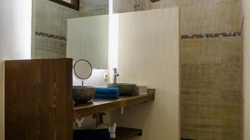 A bathroom with a wooden vanity, a mirror, a sink, and a shower.