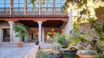 A courtyard with a covered patio, potted plants, and a stone wall.