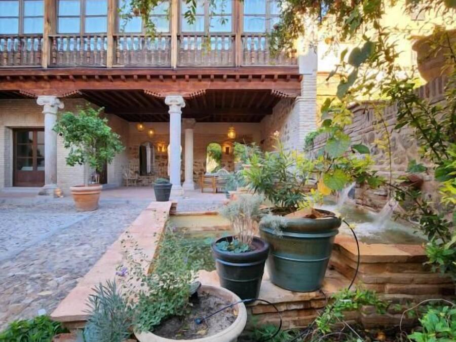 A courtyard with a covered patio, potted plants, and a stone wall.