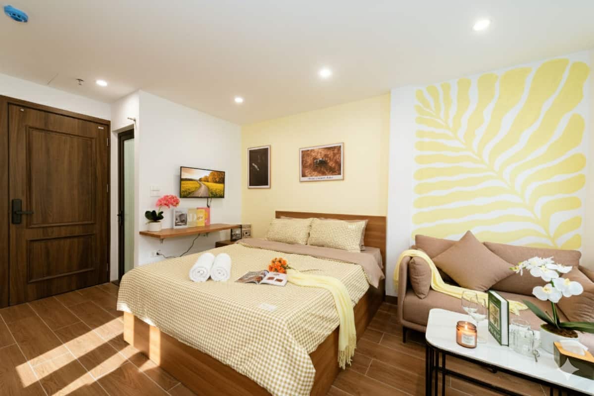 A hotel room with a bed, a sofa, a coffee table, and a TV.