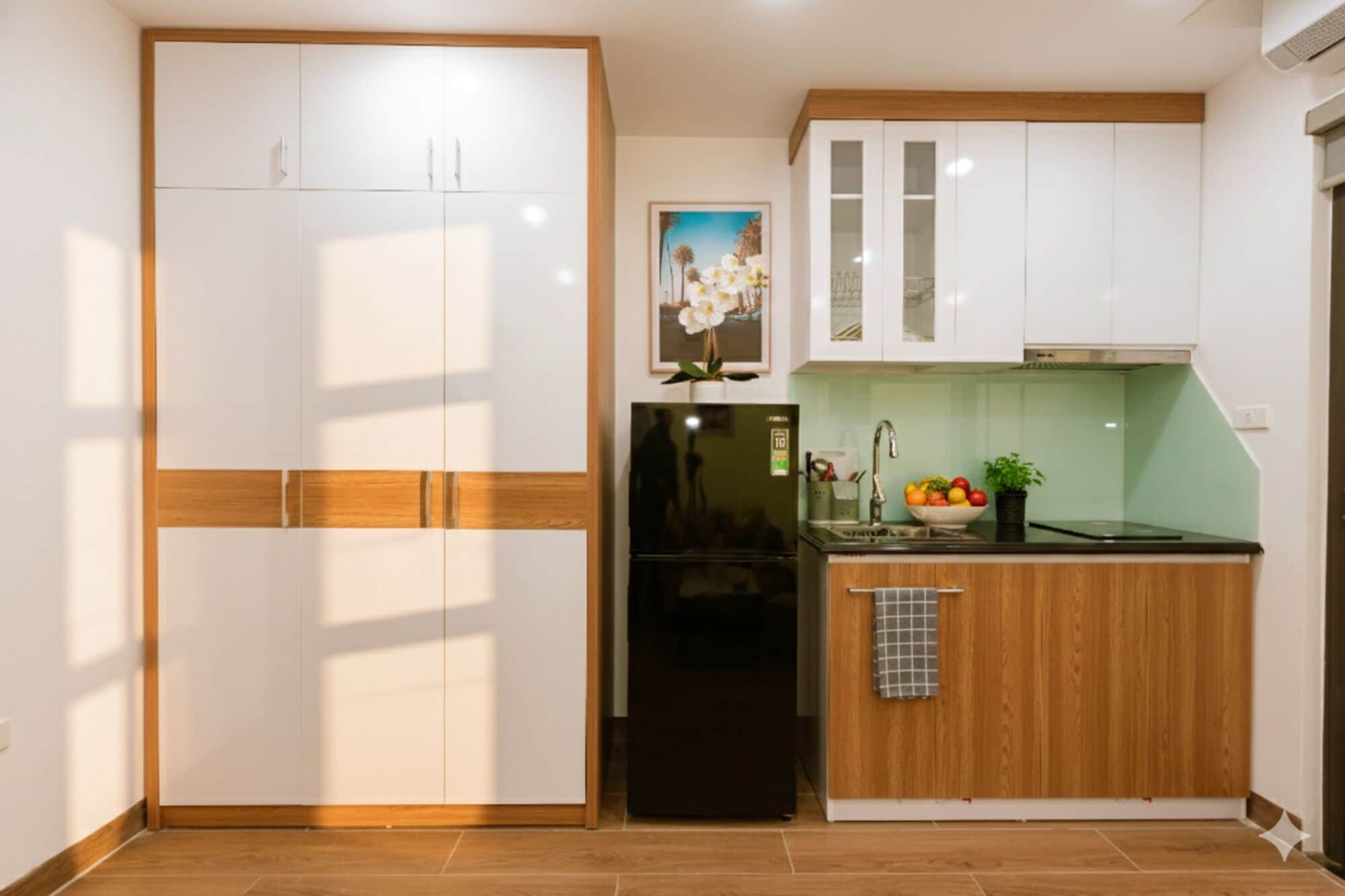 A compact kitchen with white cabinets, a black refrigerator, and a wooden countertop.