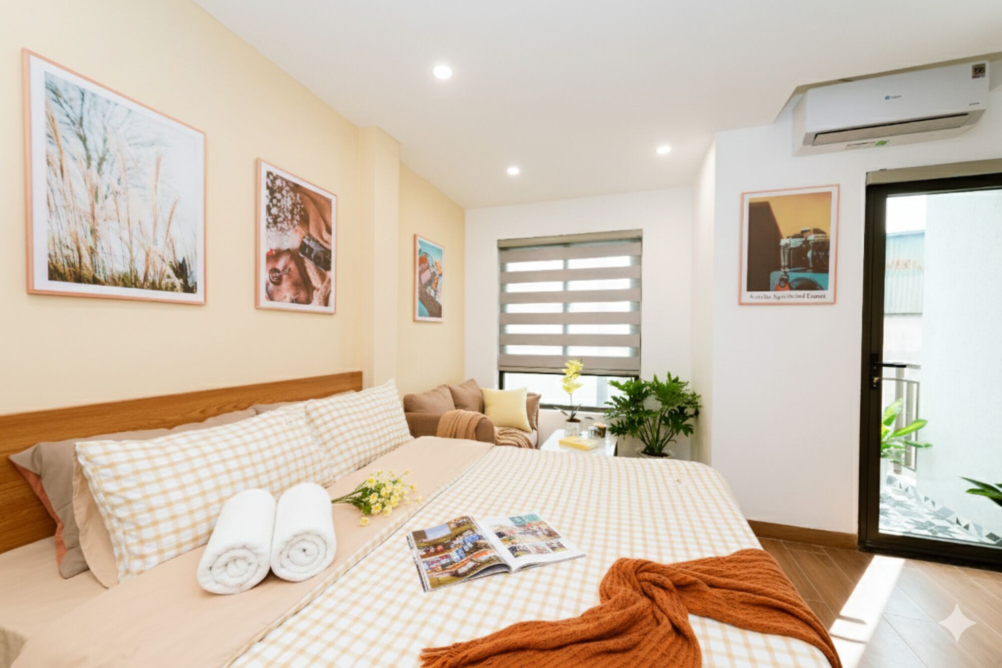 A hotel room with a large bed, a window with blinds, and a balcony with plants.